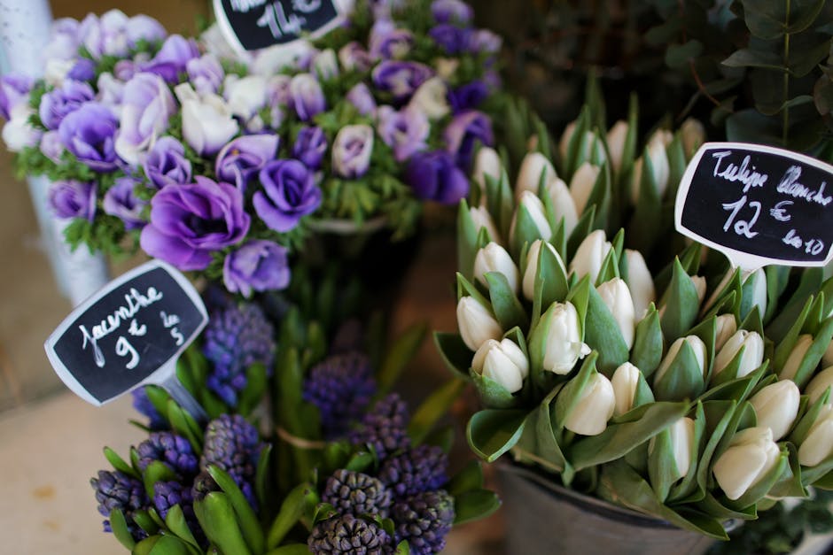 A floral display featuring fresh purple and white flowers, including a bouquet of purple lisianthus with delicate, ruffled petals and vibrant green stems, paired with a bunch of white tulips with smoo
